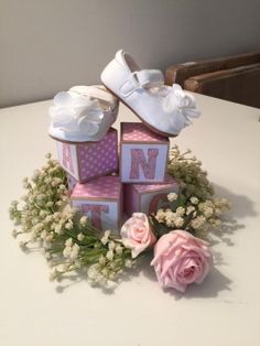 baby blocks are stacked on top of each other with pink flowers in the middle and white shoes