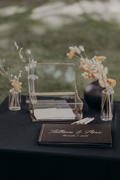 two vases filled with flowers sitting on top of a black cloth covered tablecloth