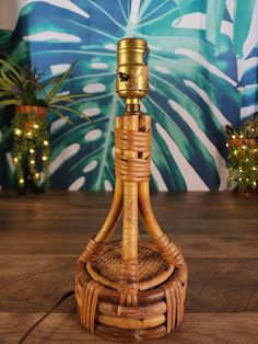 a wicker table lamp on a wooden floor in front of a wall with potted plants