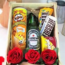 a box filled with snacks and roses on top of a table next to a bottle of beer