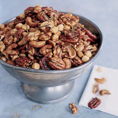 nuts in a metal bowl with rosemary sprigs on top