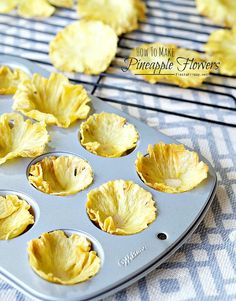 a muffin tin filled with pineapple flowers on top of a blue and white table cloth