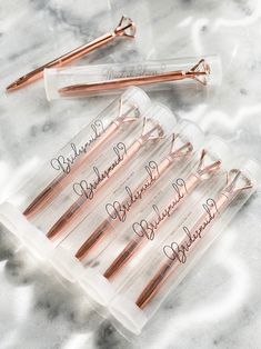 six rose gold - plated hair pins in a clear plastic case on a marble surface