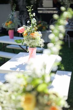 flowers are sitting in vases on white tables outside at an event or gathering,