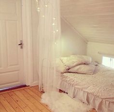 a white bed sitting in a bedroom next to a doorway with curtains on the side