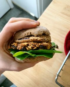 a hand holding a sandwich on top of a wooden table