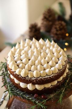 a three layer cake with marshmallows and pine cones on top, sitting on a platter