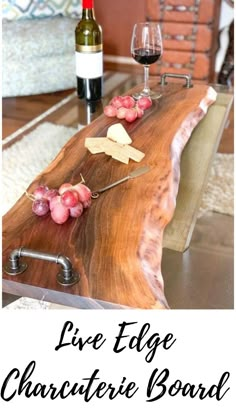 a wooden table topped with cheese and grapes next to a wine glass on top of it