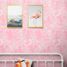 two flamingos are hanging on the pink wall next to a white crib with an orange pillow