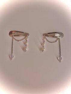 two silver hair clips with pearls and chains attached to each other on a white background