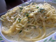 a white plate topped with pasta covered in gravy and parmesan cheese