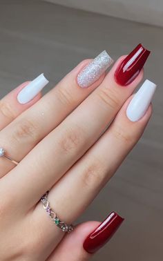 a woman's hand with red and white nail polishes on her nails, holding onto the ring