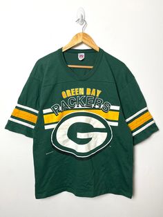 the green bay packers jersey hangs on a hanger in front of a white wall