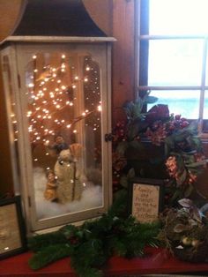 a lighted lantern sitting on top of a red table next to a christmas tree and other decorations