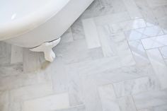 a white bath tub sitting on top of a bathroom floor next to a tiled floor