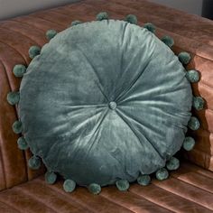 a round cushion with green pom - poms on it sitting on a couch