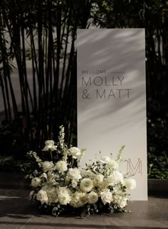 a bouquet of white flowers sitting next to a welcome sign