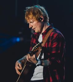 a man with red hair playing an acoustic guitar