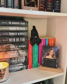 a book shelf with several books on it and a candle in the corner next to them