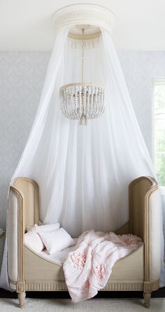 a white canopy bed with pink sheets and pillows on the bottom, in front of a window