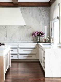 a kitchen with marble counter tops and white cabinets, along with wooden flooring that matches the ceiling