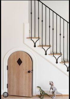 two toy dinosaurs in front of a wooden door and banister with wrought iron handrails