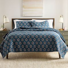 a bed with blue and white bedspread in a bedroom