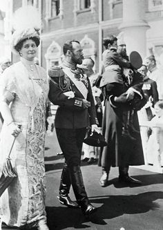 an old black and white photo of two people standing next to each other in front of a crowd