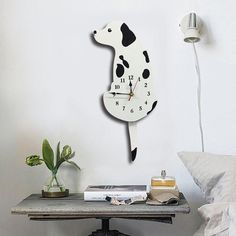 a dog clock on the wall next to a table with books and a plant in it