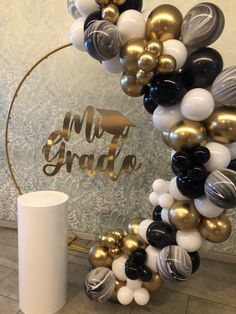 the balloon arch is decorated with black, white and gold balloons