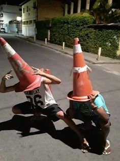 two young men playing with traffic cones on the street