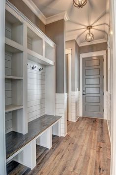 an empty room with white shelves and wood flooring on the walls, along with a light fixture