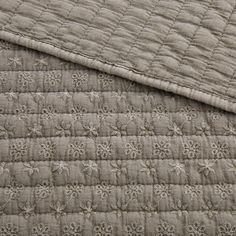 a close up view of a bed with a quilted cover and pillow on it