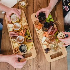 two people sitting at a table with wine glasses and cheese platters in front of them