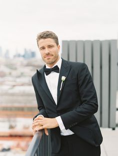 a man in a tuxedo standing on a balcony