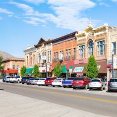 several cars parked on the side of a road in front of buildings with shops and businesses