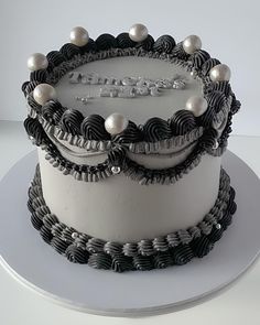 a white and black cake with pearls on top