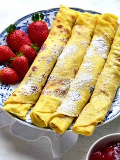 crepes on a plate with strawberries next to it