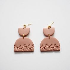 two pink earrings with waves on them