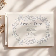 an elegant save the date card on top of a white envelope with blue floral designs