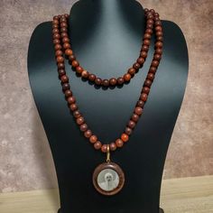 37" This Uniquely Designed Double Sided Photo Pendant Necklace Expertly Combines Wild Country Rosewood and Meditation Beads for an Elegant and Timeless Look. Handcrafted with Quality Materials, The ORIGINAL OSHO Rajneeshpuram Wild Country Rosewood Meditation Beads Mala Necklace Is the Perfect Accessory for Your Mindful Journey. ✥ Pendant size ✥ Necklace length - 37" (w/o pendant 35") ✥ Handmade by Artisans in India ❀❀❀Please look closely at photos as part of item description, the product in the Spiritual Wooden Beads Necklace For Meditation, Wooden Beads Amulet Necklace As A Gift, Amulet Style Wooden Beaded Necklace For Gifts, Amulet Style Wooden Beaded Necklace As Gift, Amulet Style Wooden Beaded Necklaces For Gifts, Wooden Beads Amulet Necklace For Gift, Holistic Wooden Beads Necklace As A Gift, Spiritual Wood Round Beads Jewelry, Holistic Style Necklace With Wooden Beads