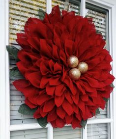 a large red flower hanging on the side of a white door with two gold balls in it