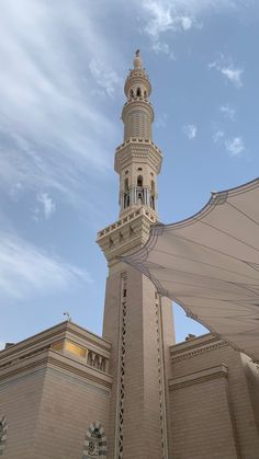 a tall building with a clock on it's side and a large white umbrella in front of it