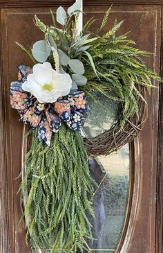 a wreath with flowers and greenery hanging on the front door for an elegant look