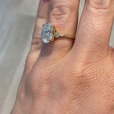 a woman's hand with a diamond ring on top of her finger and an engagement band