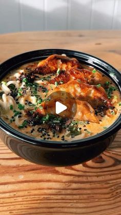 a black bowl filled with food on top of a wooden table