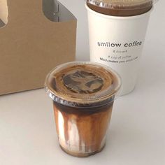 two coffee cups sitting next to each other in front of a cardboard box with the lid open