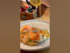 a white plate topped with food on top of a wooden table next to a glass of wine