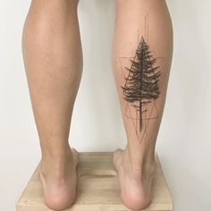 a person standing on top of a wooden platform with their legs covered in tattoos and pine trees