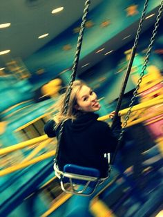 a woman is sitting on a swing in a carnival ride at the park or amusement